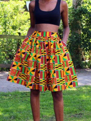 A vibrant African kente skirt featuring an orange and green print, designed with side pockets and a small zipper.