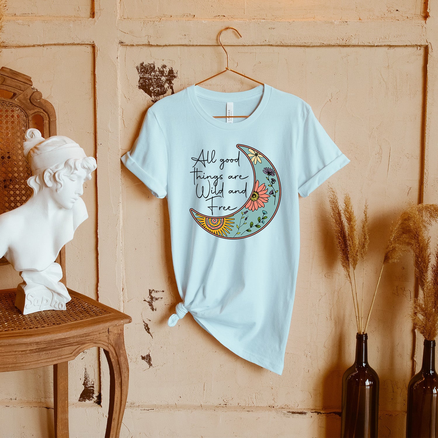 All Good Things Are Wild and Free Moon Unisex T-shirt featuring a moon graphic, showcasing its soft fabric and vibrant colors.