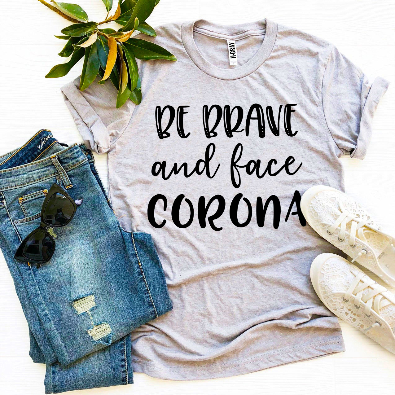Be Brave & Face Corona T-shirt in various sizes, showcasing its soft fabric and vibrant print.