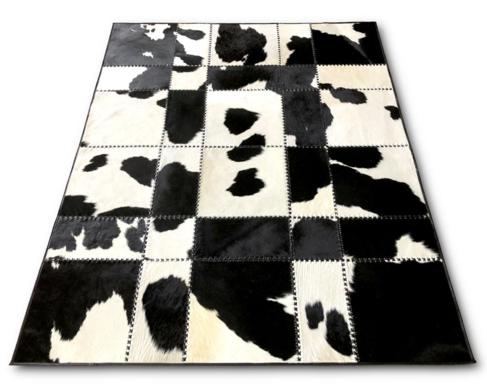 Handmade black and white patchwork cow skin rug, showcasing a luxurious design with natural leather texture.