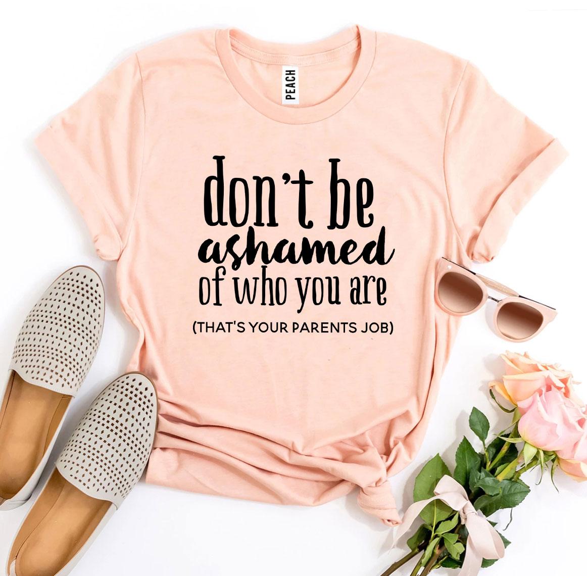 A stylish black t-shirt featuring the phrase 'Don’t Be Ashamed Of Who You Are' in bold print, made from soft ring spun cotton.