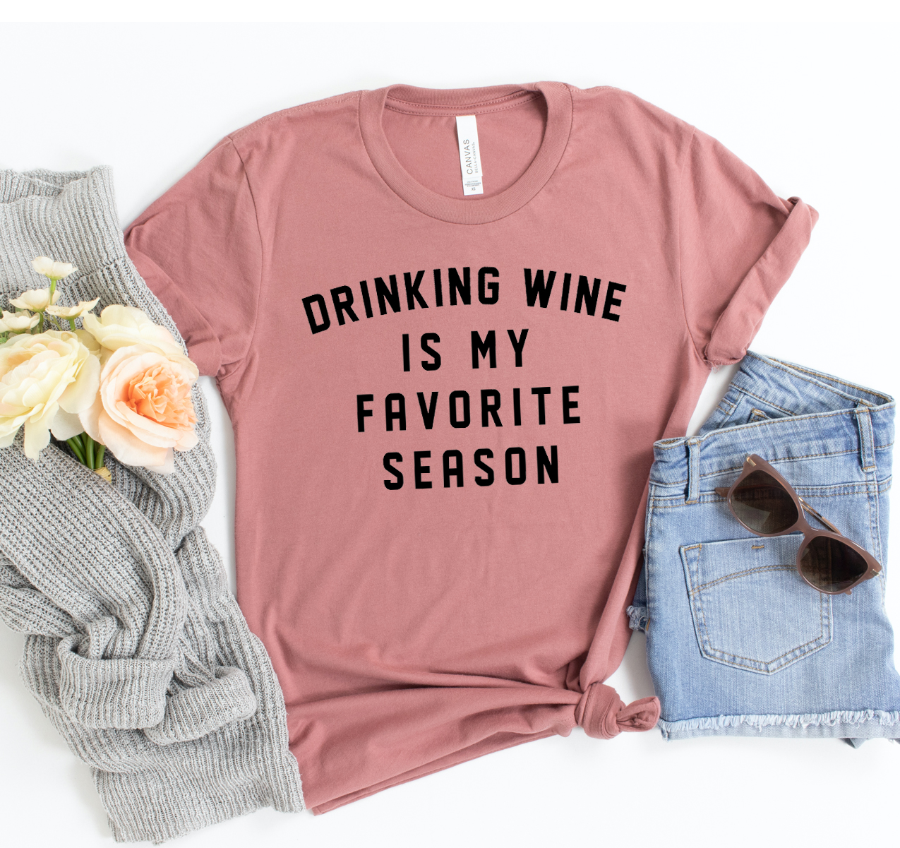 A stylish unisex t-shirt featuring the phrase 'Drinking Wine Is My Favorite Season' in a fun font, made from soft airlume cotton.