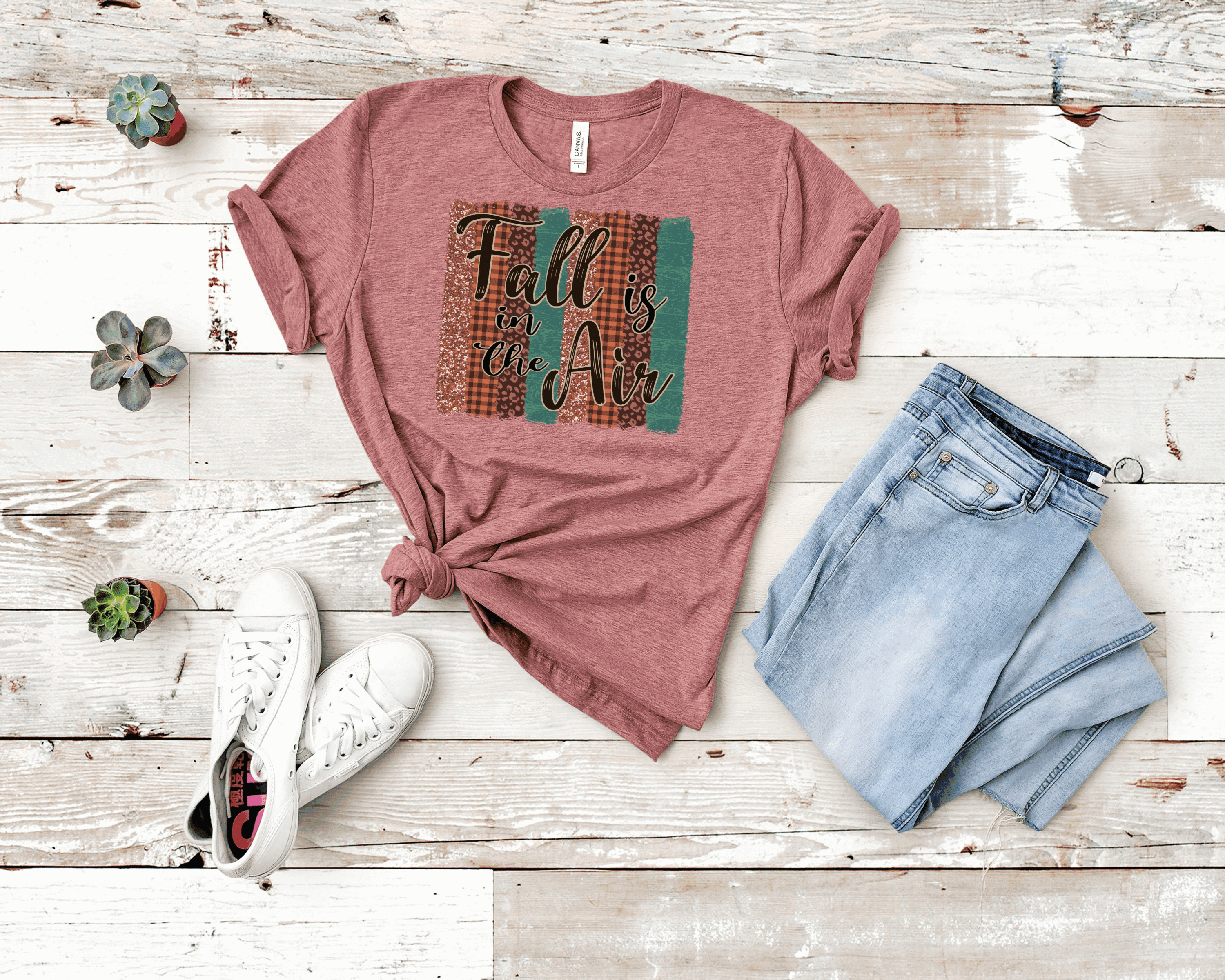 A cozy Fall Is In The Air graphic tee featuring autumn-themed design on a soft Bella Canvas fabric.