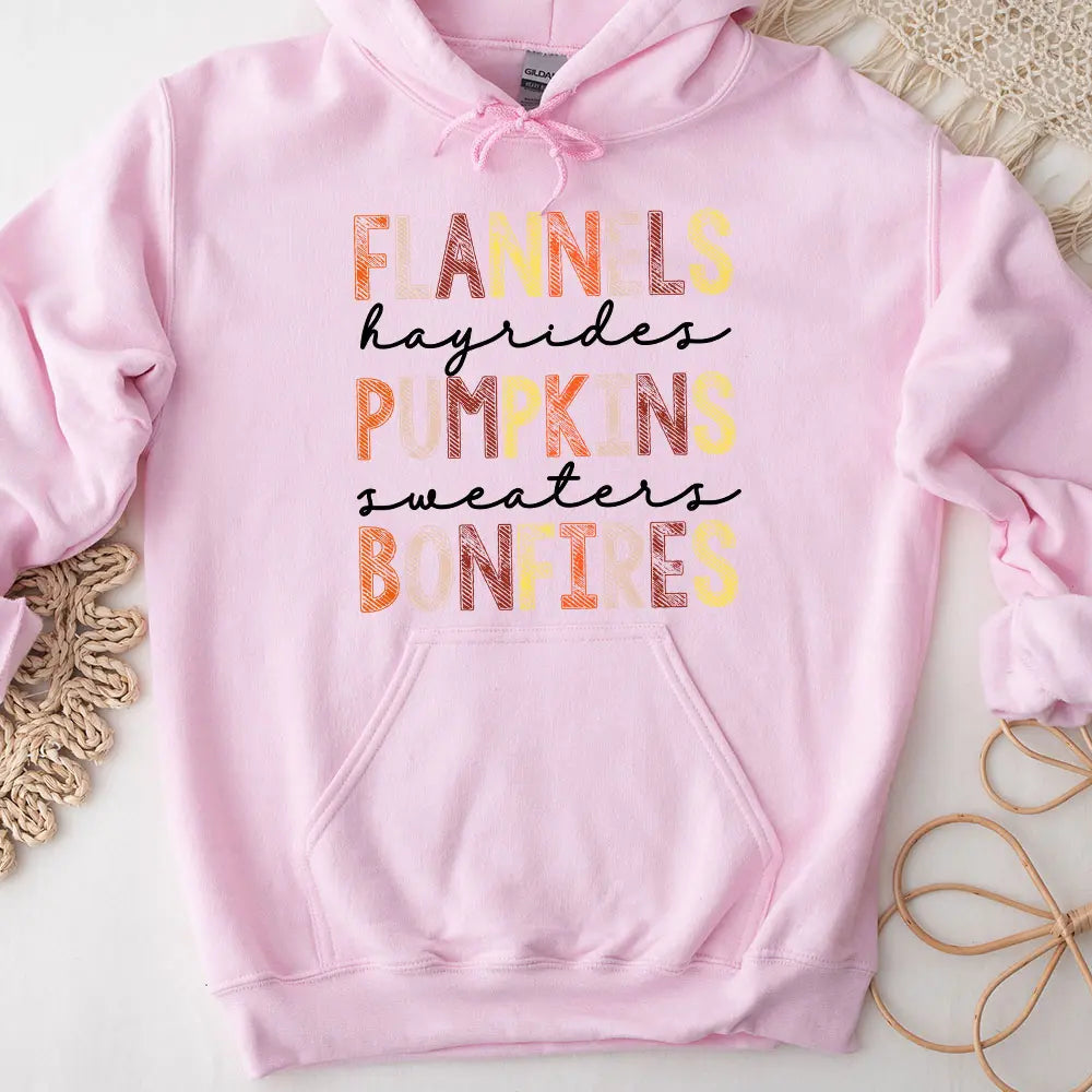 Cozy Flannels Hayrides Pumpkins Sweaters Bonfires Hoodie displayed on a rustic wooden background, showcasing its autumn-themed design.