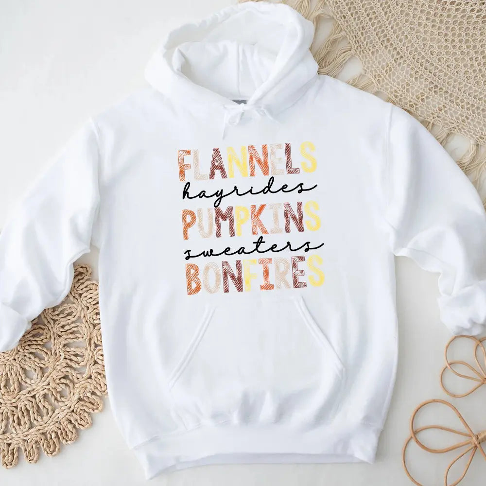Cozy Flannels Hayrides Pumpkins Sweaters Bonfires Hoodie displayed on a rustic wooden background, showcasing its autumn-themed design.
