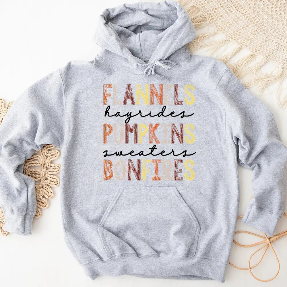 Cozy Flannels Hayrides Pumpkins Sweaters Bonfires Hoodie displayed on a rustic wooden background, showcasing its autumn-themed design.