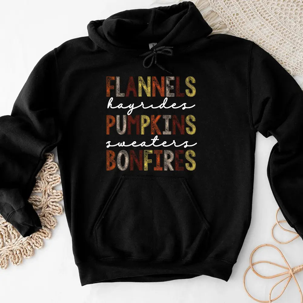 Cozy Flannels Hayrides Pumpkins Sweaters Bonfires Hoodie displayed on a rustic wooden background, showcasing its autumn-themed design.