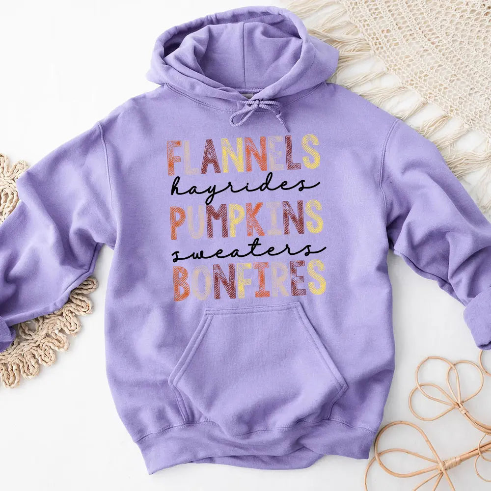 Cozy Flannels Hayrides Pumpkins Sweaters Bonfires Hoodie displayed on a rustic wooden background, showcasing its autumn-themed design.