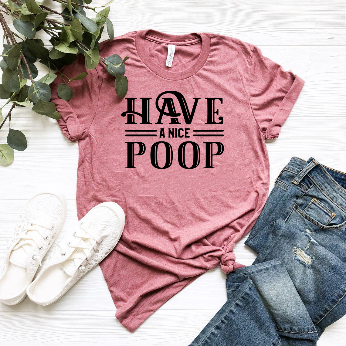 A unisex T-shirt featuring the humorous phrase 'Have A Nice Poop' printed on it, made from soft ring spun cotton, available in multiple colors.