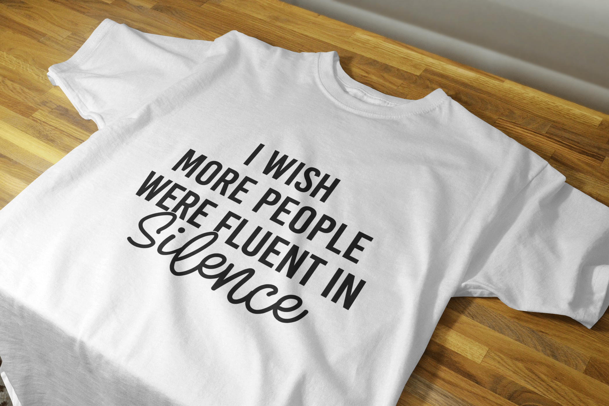 Black unisex shirt featuring the phrase 'I Wish More People Were Fluent In Silence' in white lettering, showcasing a classic fit and comfortable design.