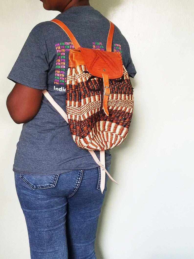 Colorful Kiondo African backpack made of sisal with stitched leather straps, showcasing unique patterns and handmade craftsmanship.