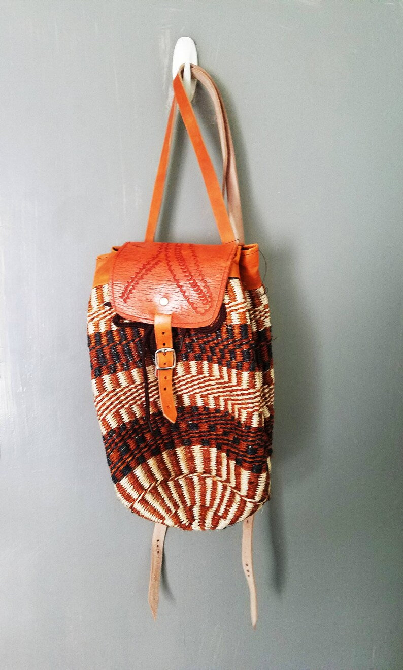 Colorful Kiondo African backpack made of sisal with stitched leather straps, showcasing unique patterns and handmade craftsmanship.