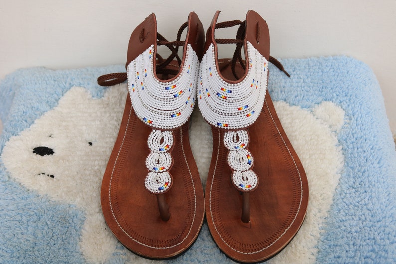 A pair of handmade Maasai African sandals featuring colorful beadwork and soft leather, perfect for summer wear.