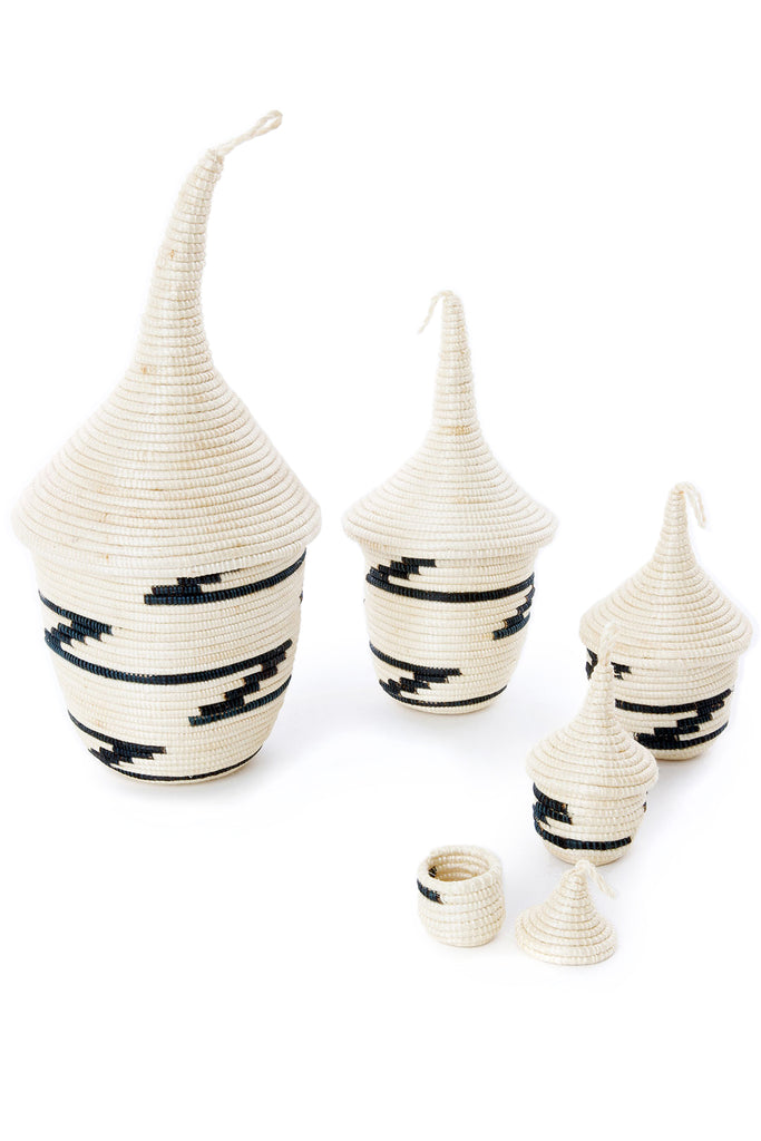 A beautiful set of five handcrafted Rwanda nesting baskets made from natural sisal, showcasing unique designs in shades of black and dark blue.