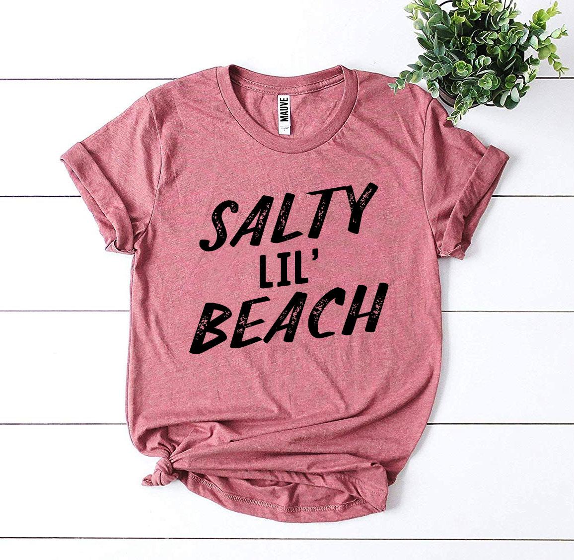 Salty Lil’ Beach T-shirt made from premium ring spun cotton, featuring a vibrant design and available in multiple sizes.