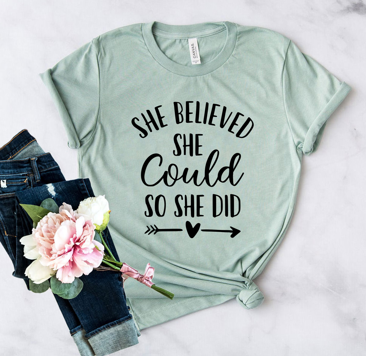 A unisex T-shirt featuring the motivational quote 'She Believed That She Could So She Did', made from soft ring spun cotton, available in various colors.