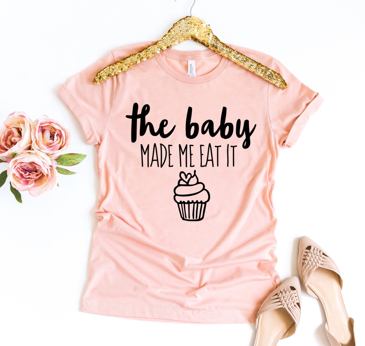 The Baby Made Me Eat It T-shirt in various sizes, showcasing its soft cotton fabric and humorous print.