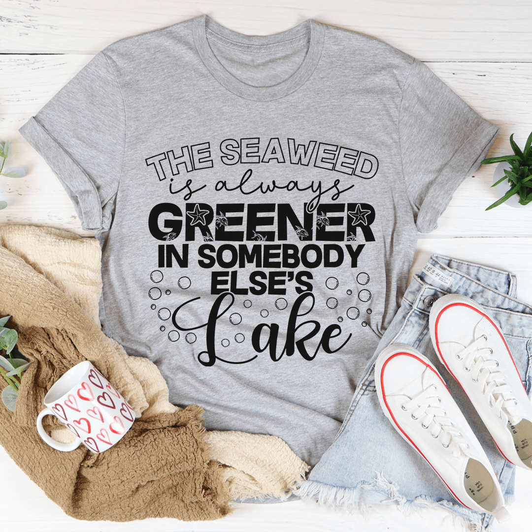 A classic unisex short sleeve tee featuring the phrase 'The Seaweed Is Always Greener In Somebody Else's Lake' in vibrant colors on soft cotton fabric.