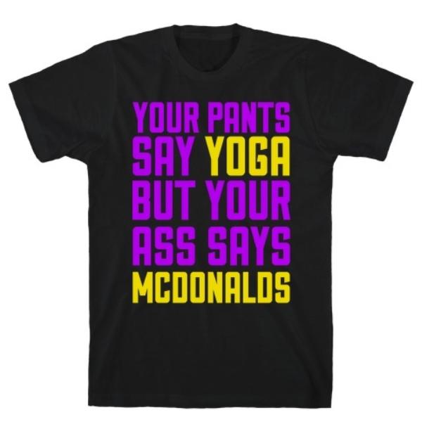 A humorous t-shirt featuring the phrase 'Your Pants Say Yoga But Your Ass Says McDonald's' printed on a soft cotton fabric.