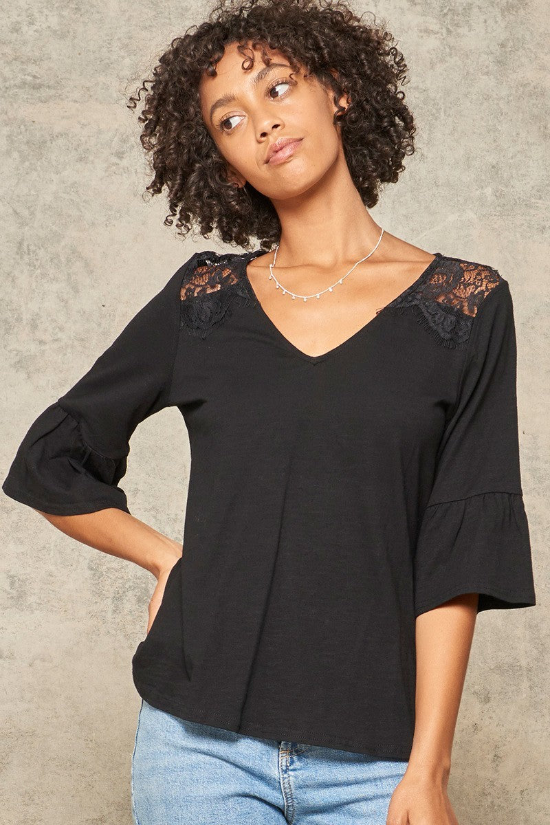 A stylish black knit top featuring a deep V neckline, yoke design, and floral eyelash lace with 3/4 trumpet sleeves and flared ruffle cuffs.