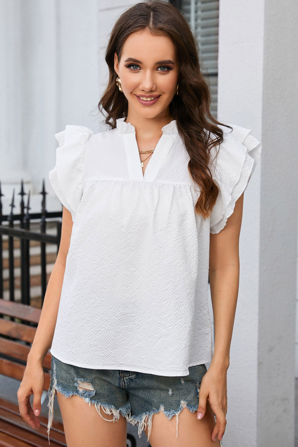 A stylish white top featuring ruffle accents and flutter sleeves, designed with a notch neck for an elegant look.