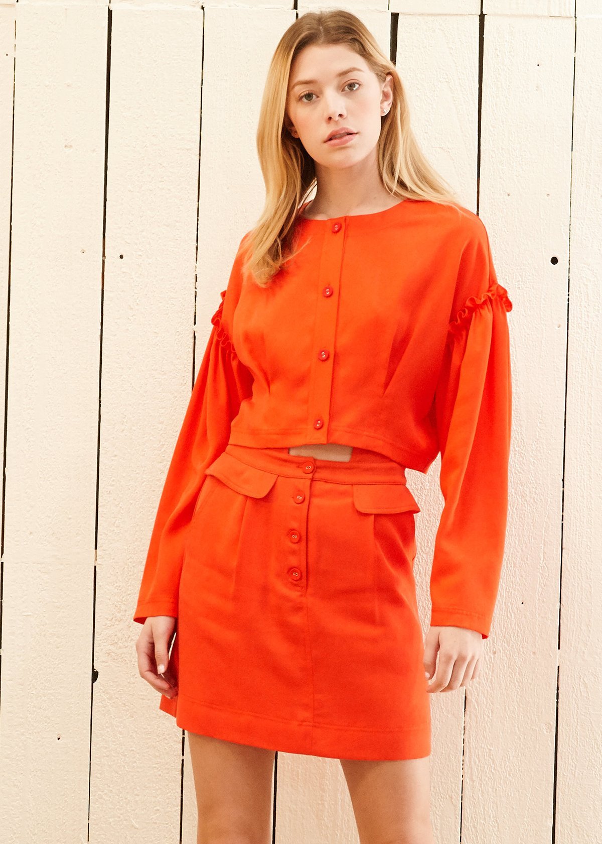 Women's Button Front Long Sleeve Crop Top in vibrant poppy color with drop shoulder and ruffle accent, showcasing button fly closure.