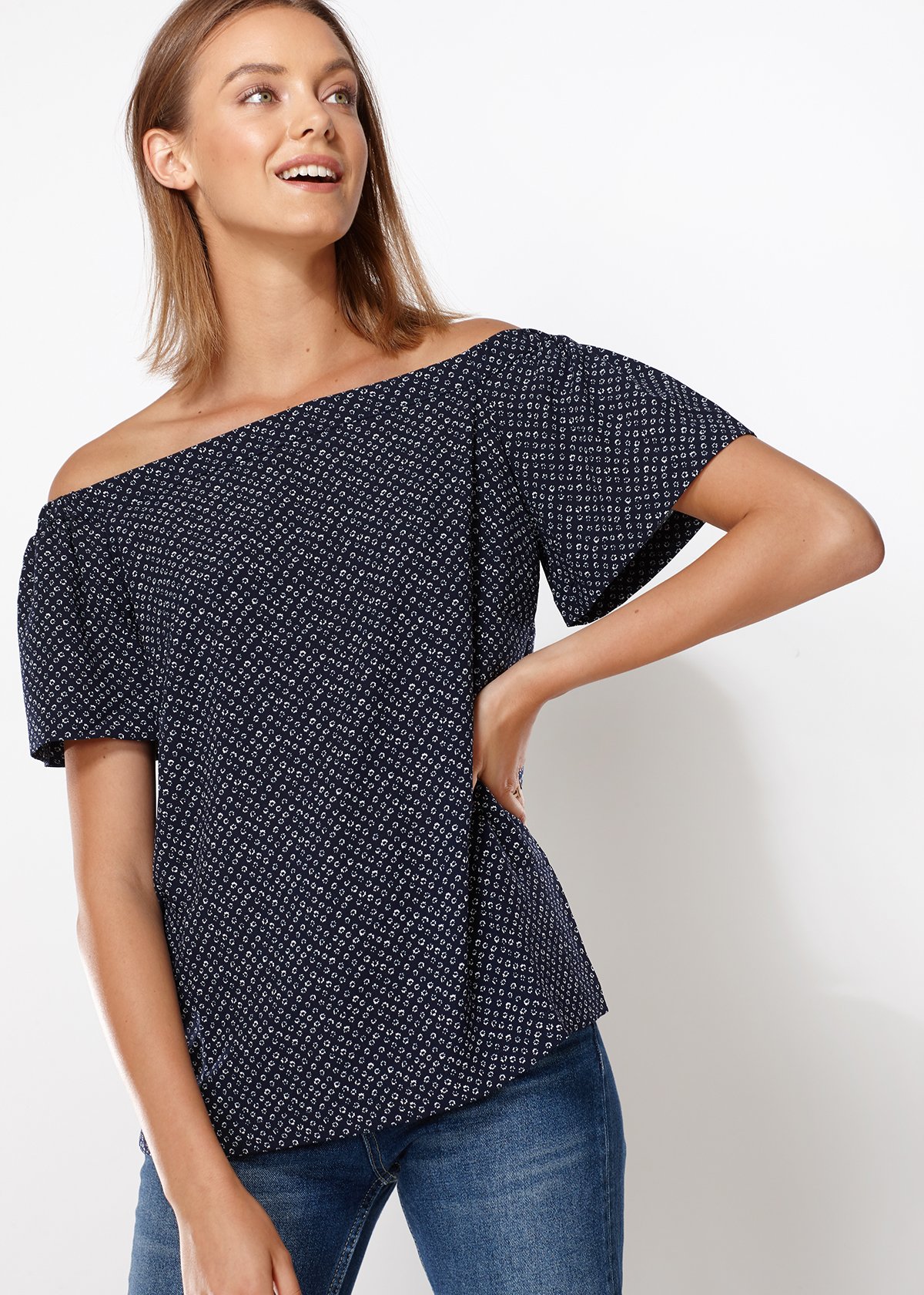 Women's off-shoulder top in navy with tiny foot pattern, featuring short bell sleeves and an elasticized shoulder line.