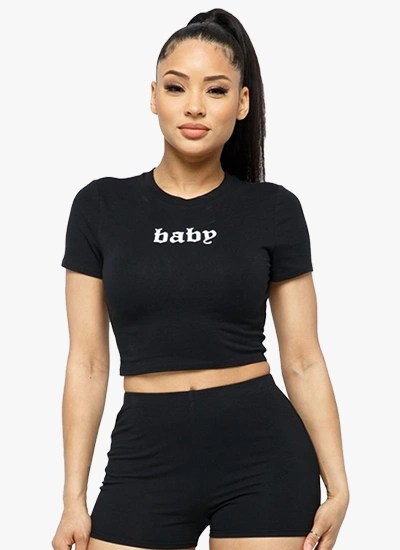 A stylish woman wearing a 2-piece short sleeve outfit set, featuring a round neck crop top and matching shorts in a solid color, perfect for active wear.