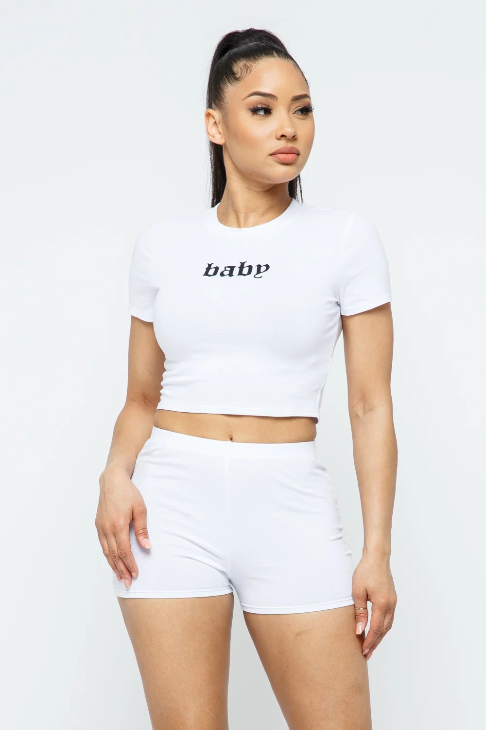 A stylish woman wearing a 2-piece short sleeve outfit set, featuring a round neck crop top and matching shorts in a solid color, perfect for active wear.