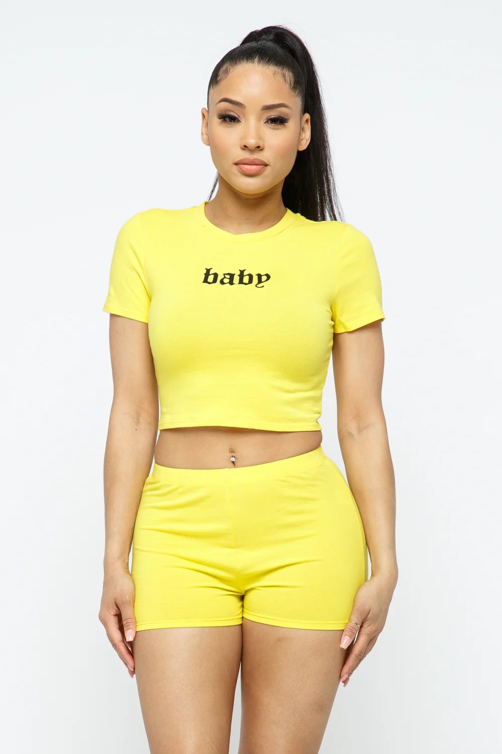 A stylish woman wearing a 2-piece short sleeve outfit set, featuring a round neck crop top and matching shorts in a solid color, perfect for active wear.