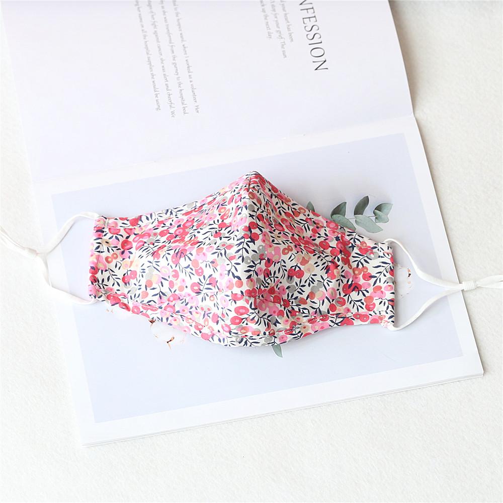 Two stylish Cherry Dream cotton face masks with nose wire and filter pocket, showcasing unique prints and adjustable ear loops.