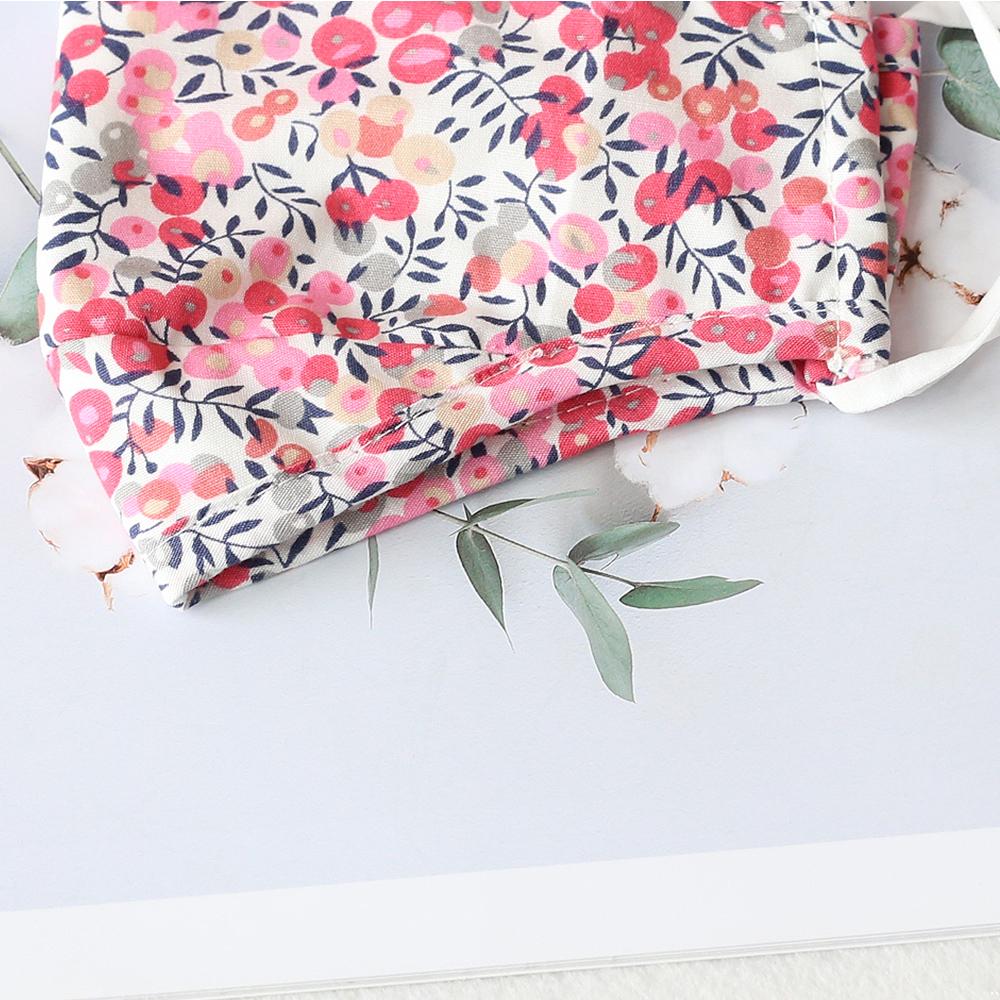 Two stylish Cherry Dream cotton face masks with nose wire and filter pocket, showcasing unique prints and adjustable ear loops.