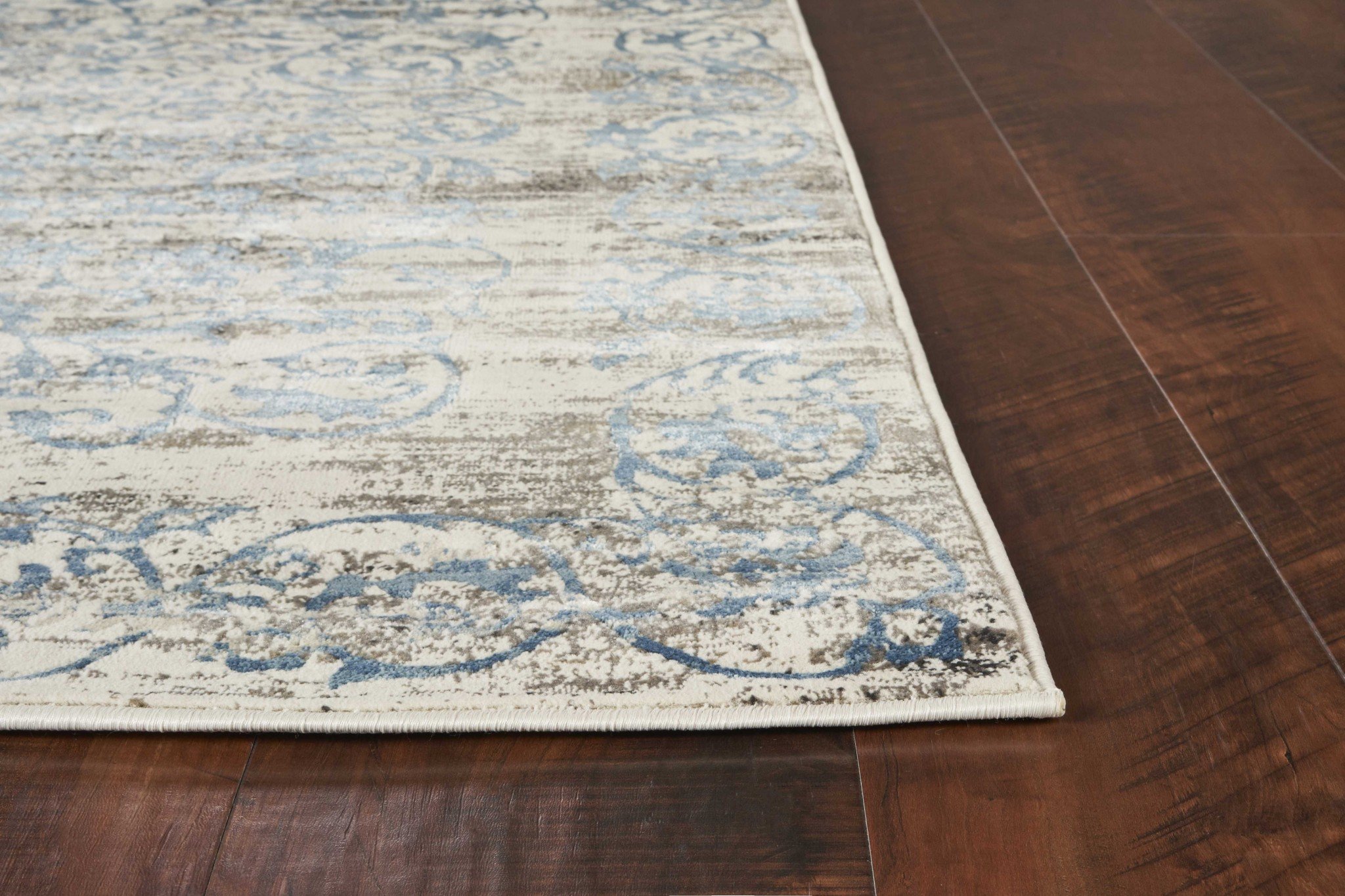 7'x10' Ivory Blue Machine Woven Distressed Floral Traditional Indoor rug with intricate patterns and soft sheen highlights.