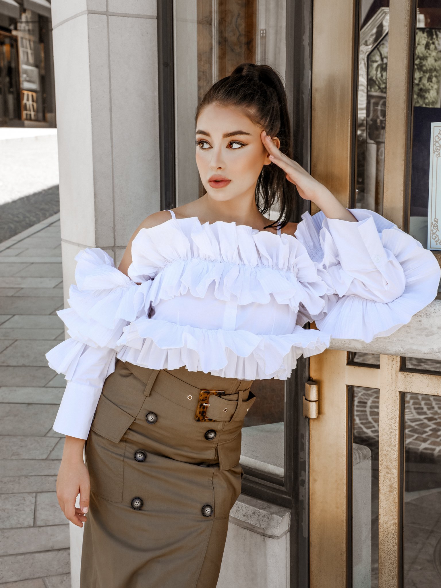 A stylish woman wearing the After Hours Ruffle Shirt, showcasing its off-the-shoulder design and elegant ruffles.