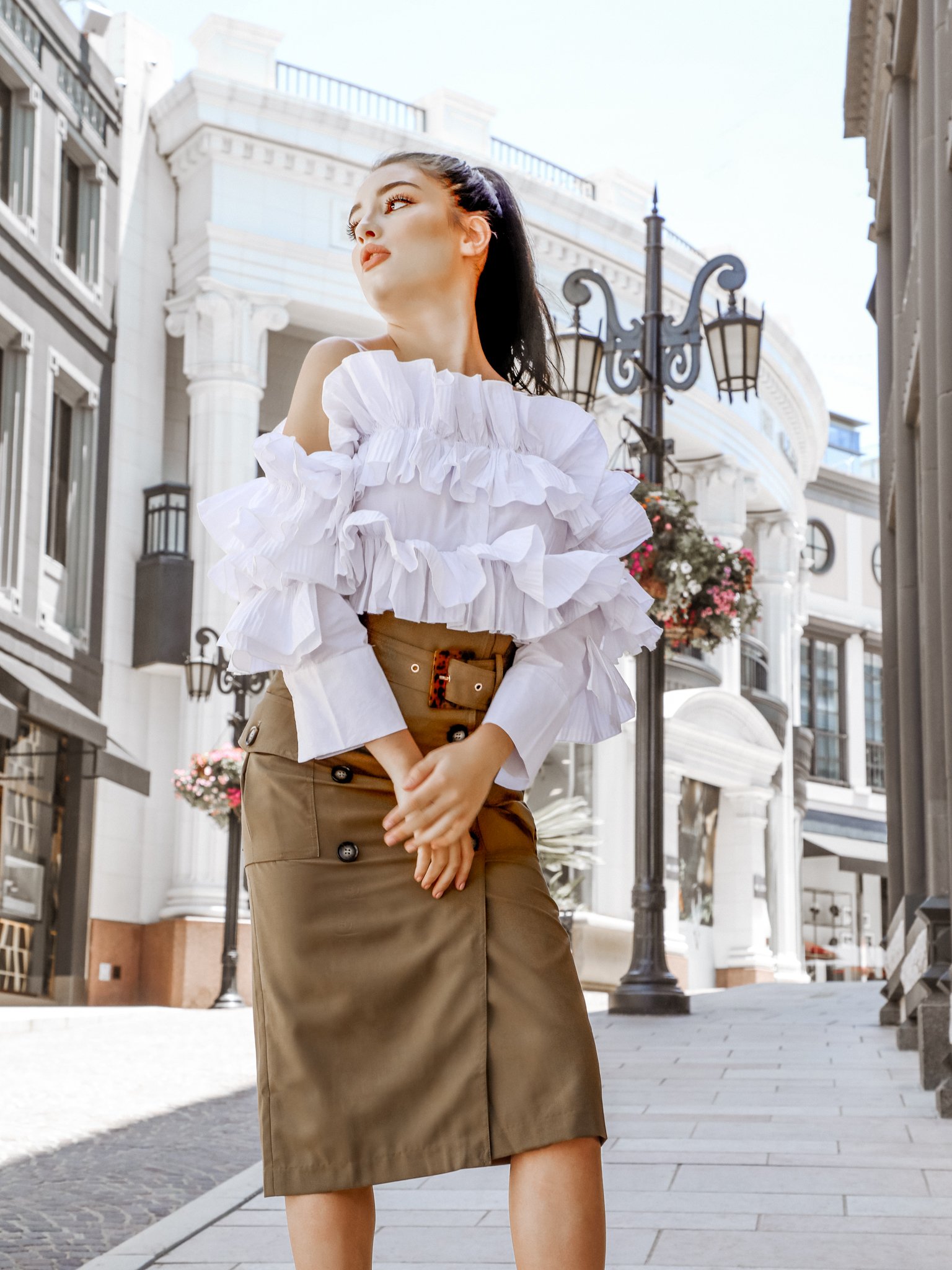 A stylish woman wearing the After Hours Ruffle Shirt, showcasing its off-the-shoulder design and elegant ruffles.