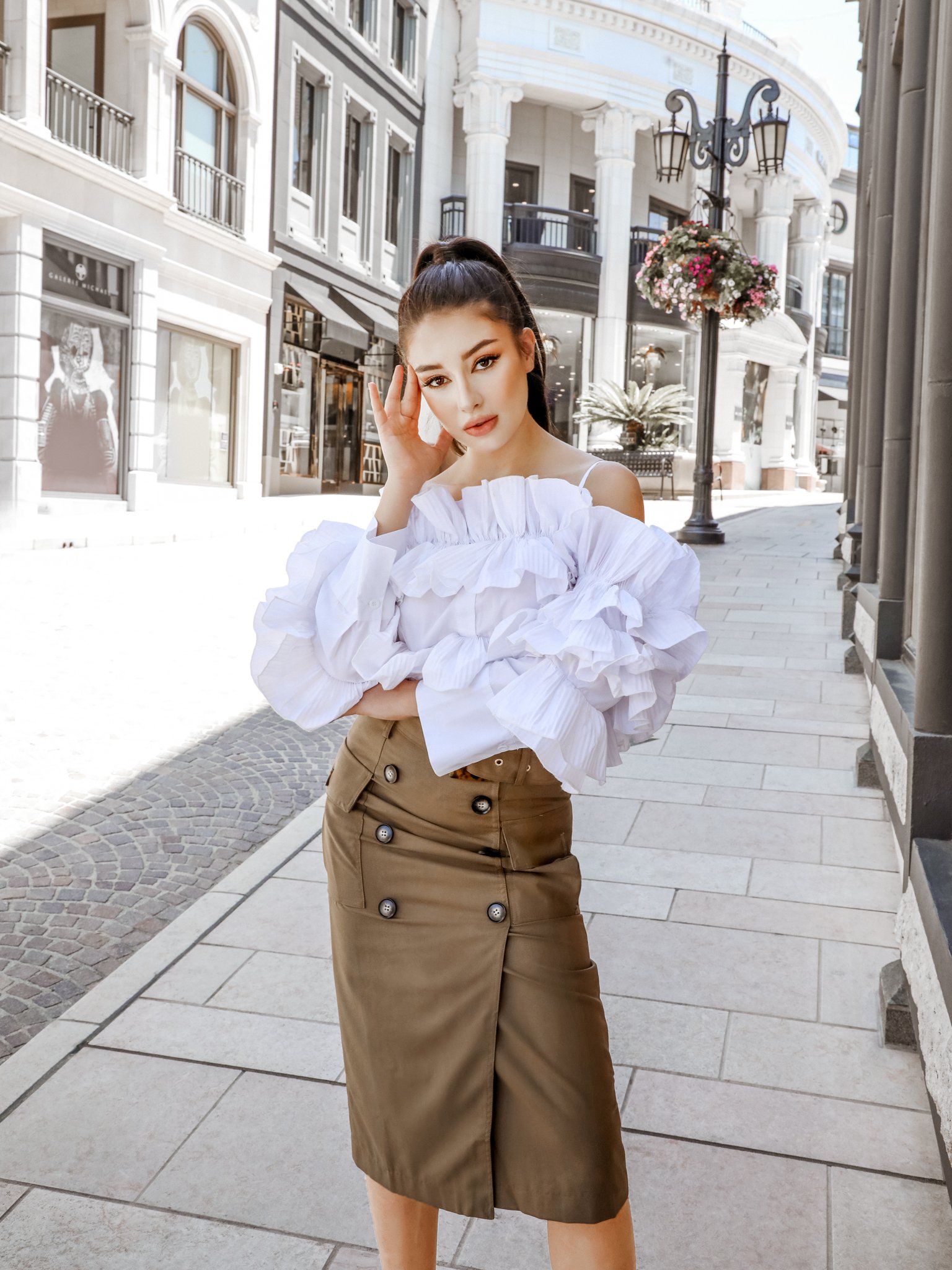 A stylish woman wearing the After Hours Ruffle Shirt, showcasing its off-the-shoulder design and elegant ruffles.