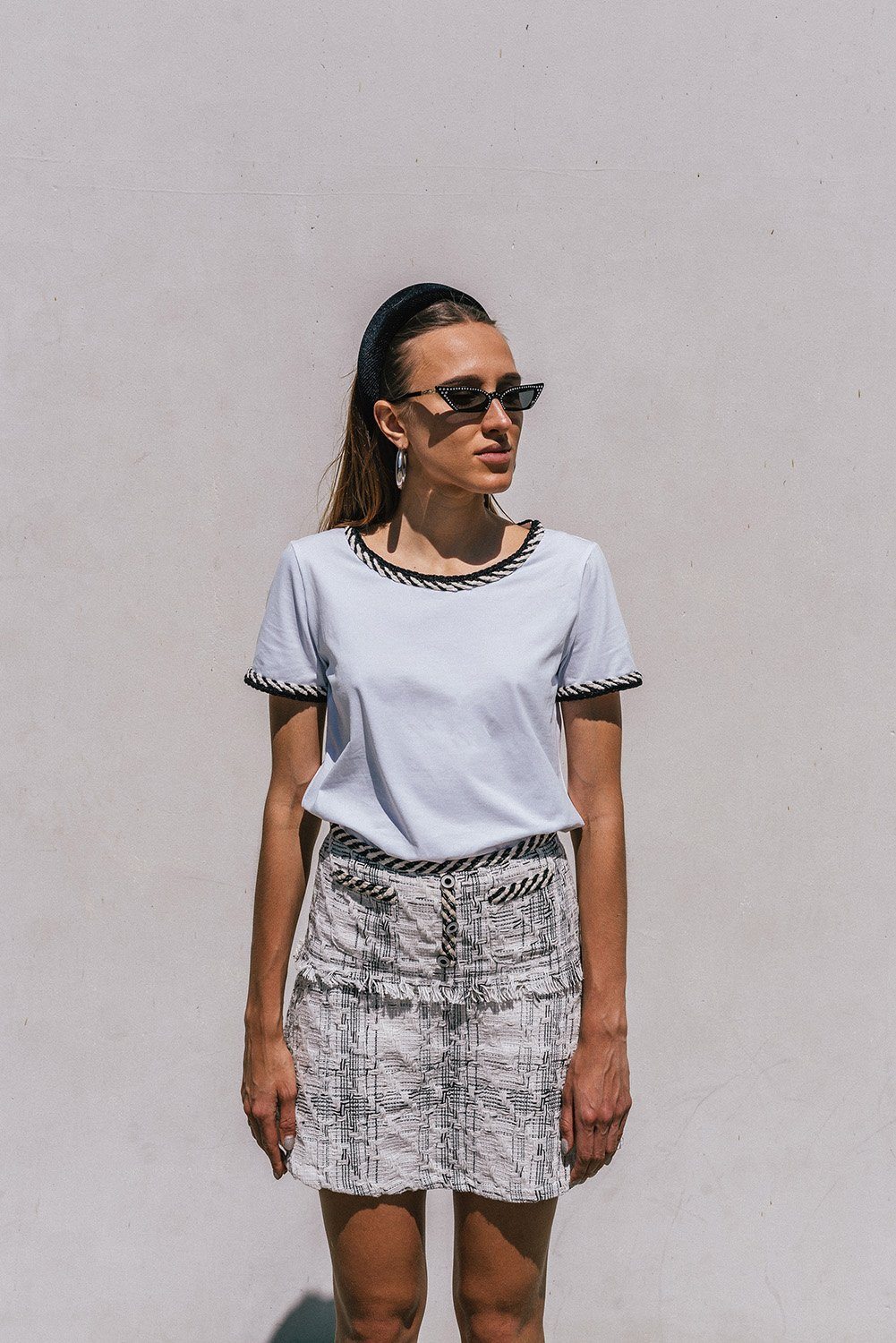 Ambre White T-shirt featuring trendy tweed detailing and a round neckline, styled with a mini-skirt.