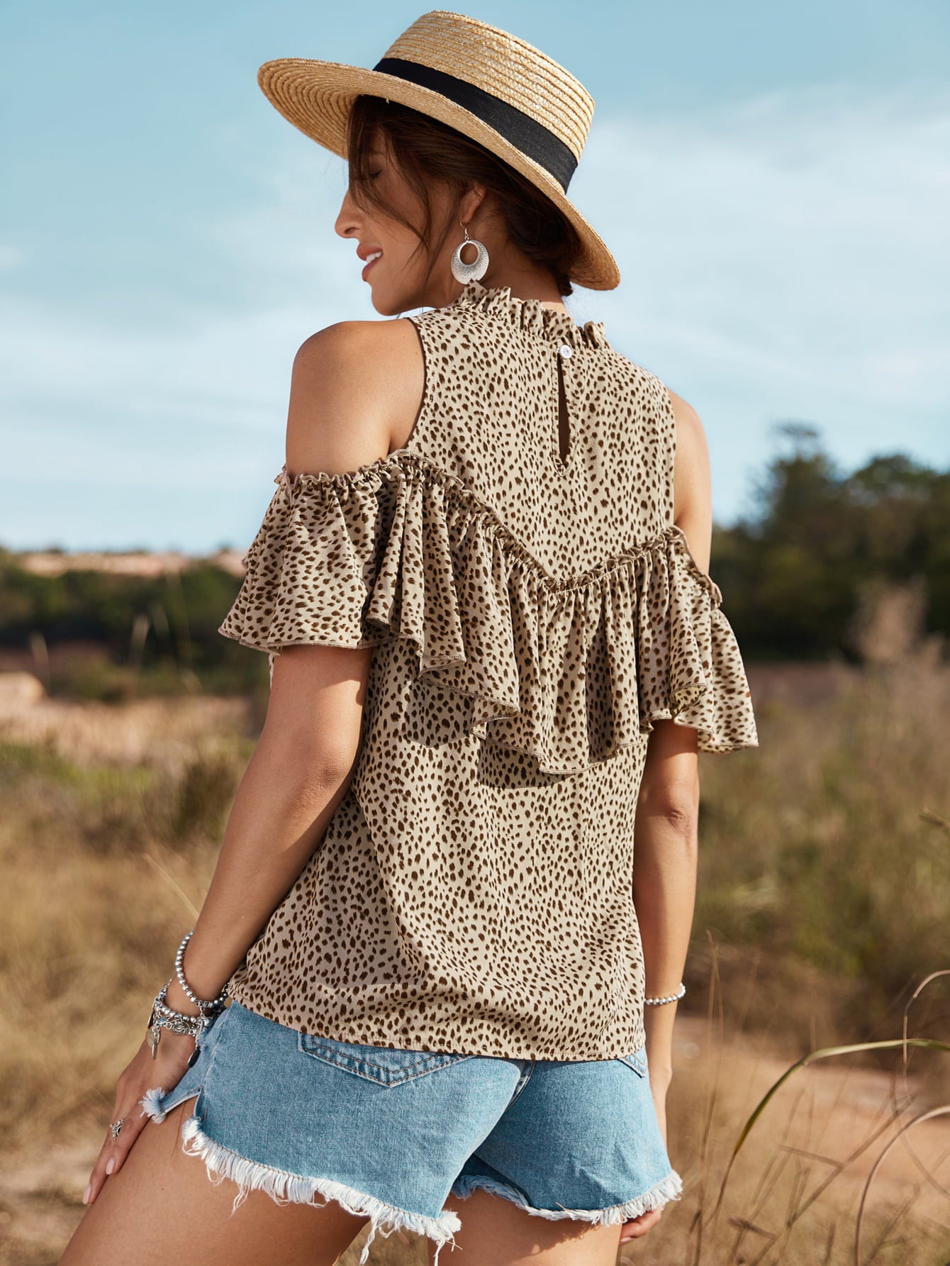 A stylish animal print cold-shoulder ruffled blouse displayed on a mannequin, showcasing its trendy design and casual elegance.