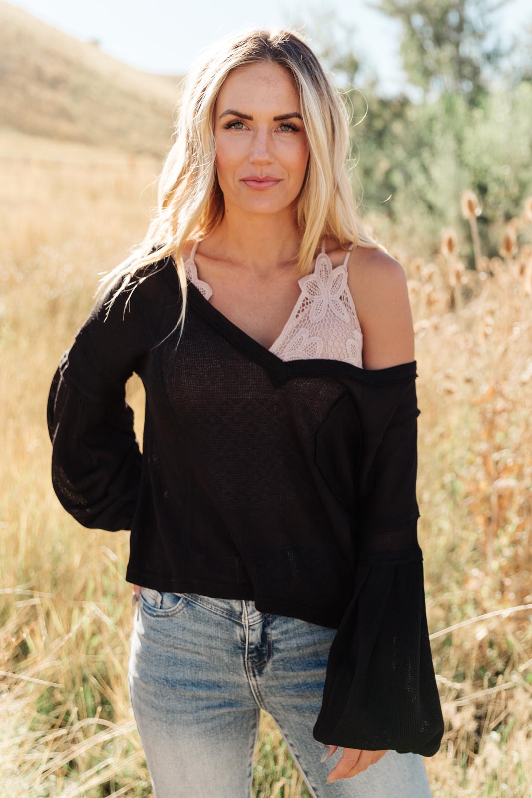 Bellissimo Draped V-Neck Sweater in Black, showcasing its deep V-neckline and raw stitching details.