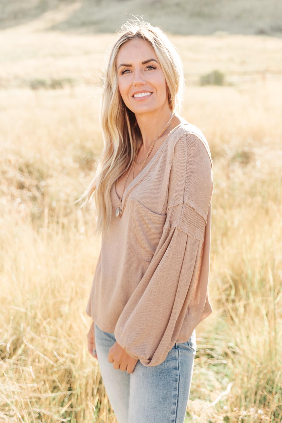 Bellissimo Draped V-Neck Sweater in Mocha, showcasing its deep V-neckline and raw stitching details.