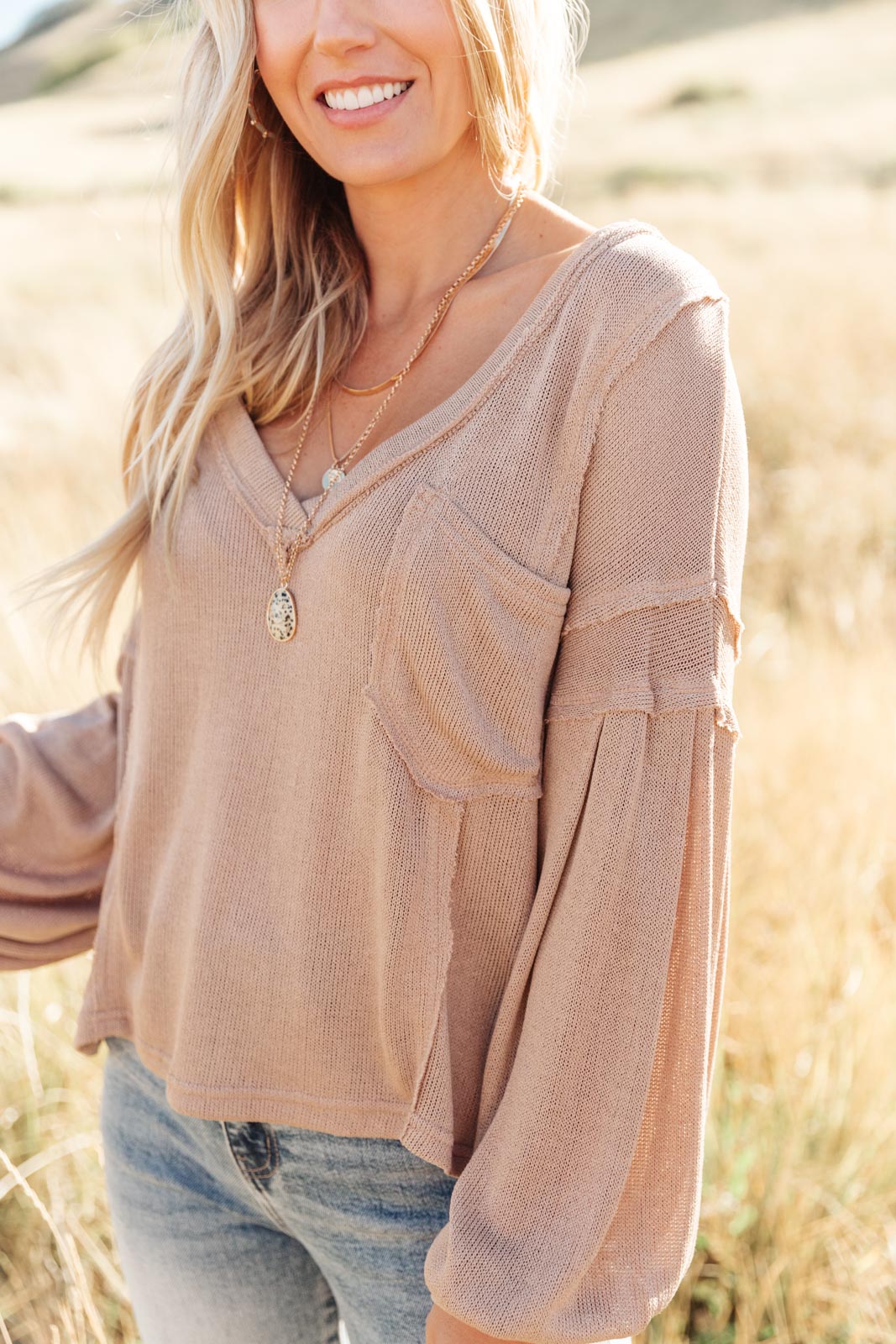 Bellissimo Draped V-Neck Sweater in Mocha, showcasing its deep V-neckline and raw stitching details.