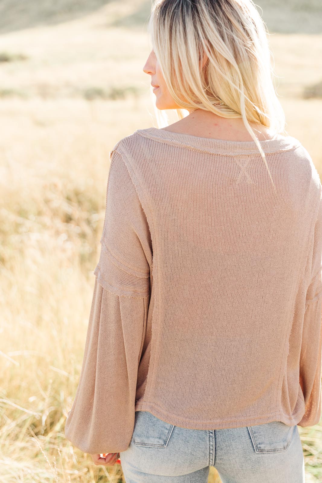 Bellissimo Draped V-Neck Sweater in Mocha, showcasing its deep V-neckline and raw stitching details.