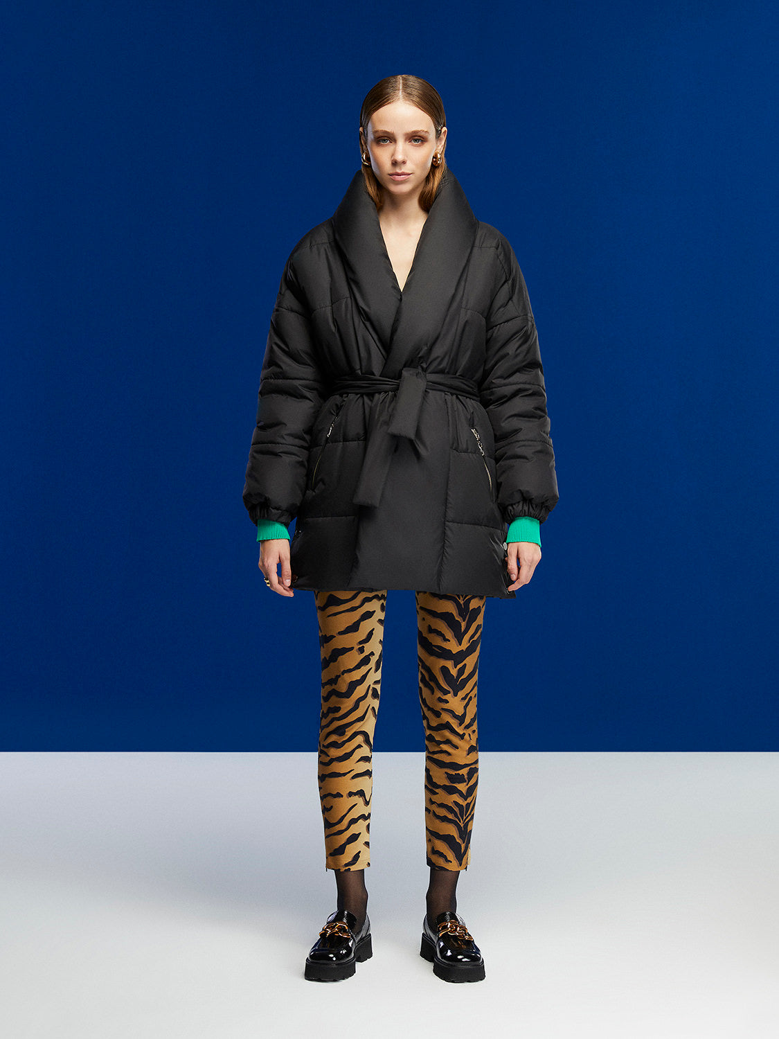 A stylish belted puffer jacket featuring a double-breasted design, wide neck, and side zipper pockets, perfect for winter fashion.