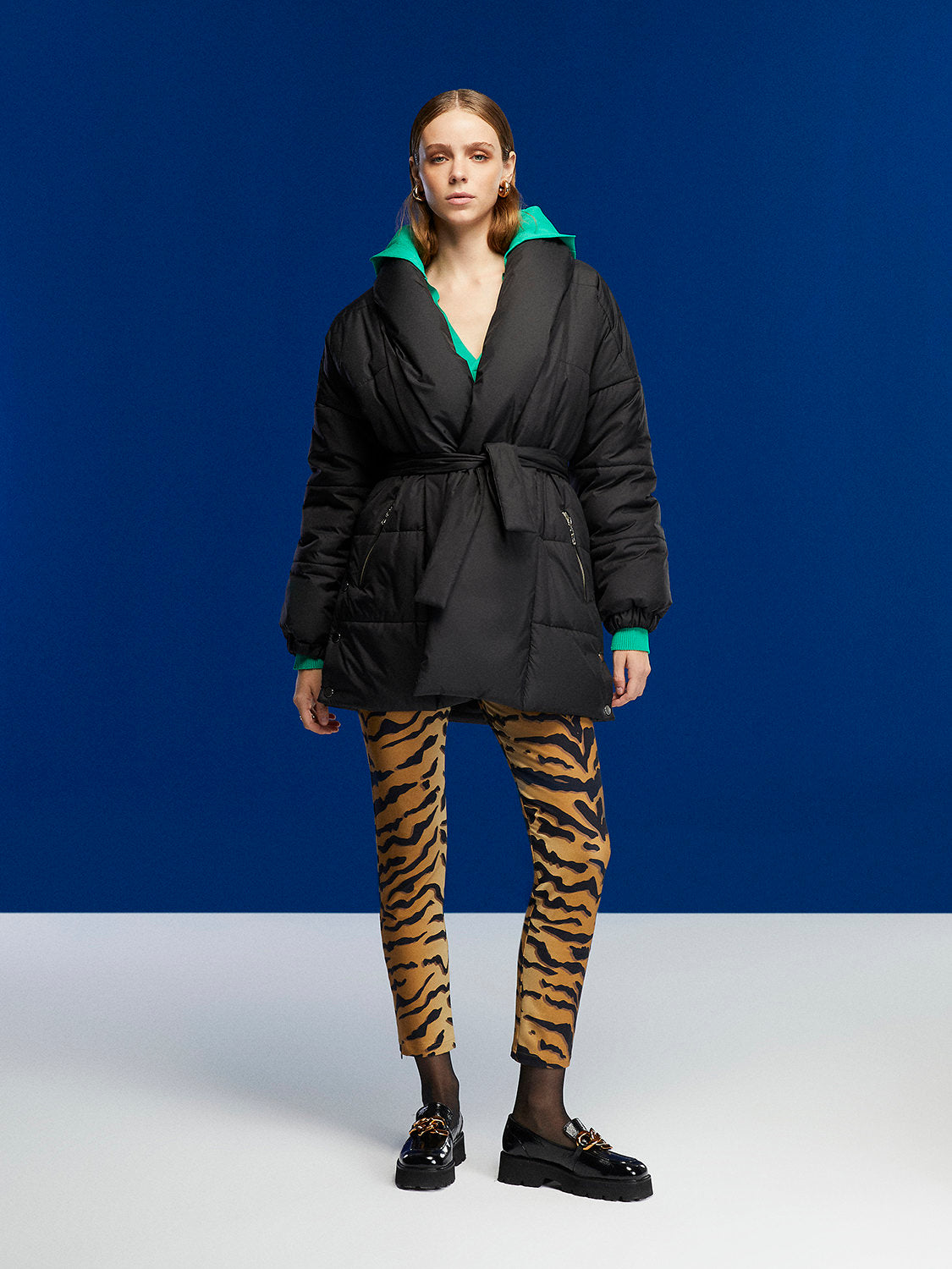 A stylish belted puffer jacket featuring a double-breasted design, wide neck, and side zipper pockets, perfect for winter fashion.