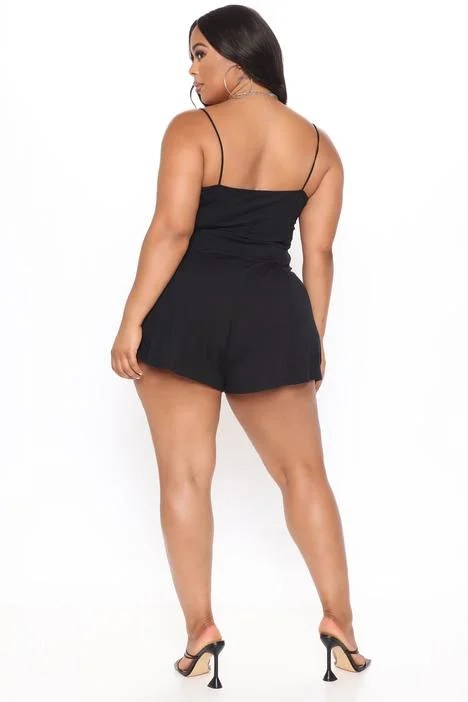 A stylish black romper featuring thin bungee straps and flowy shorts, perfect for casual and dressy occasions.