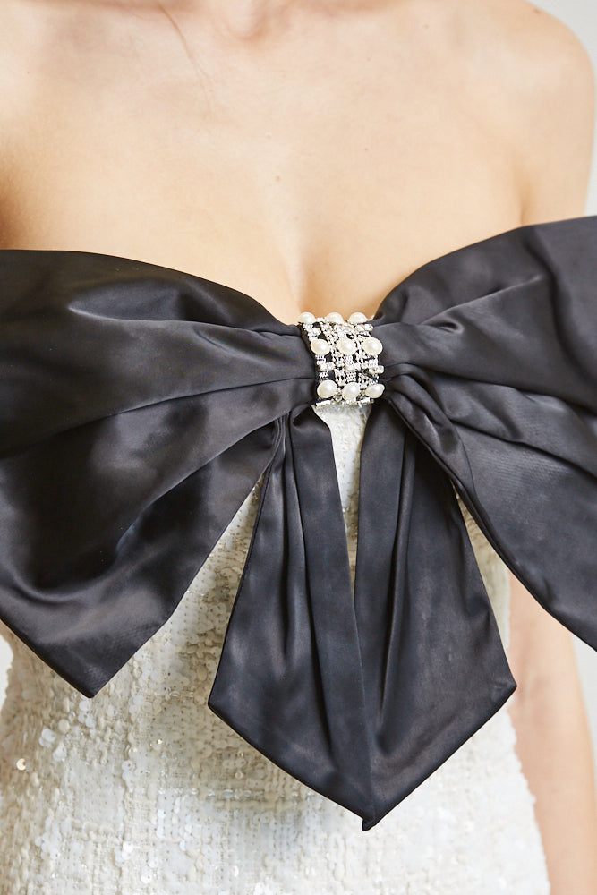 The Blakely dress showcasing sequined tweed fabric, strapless neckline, and satin bow trim with rhinestone detailing.