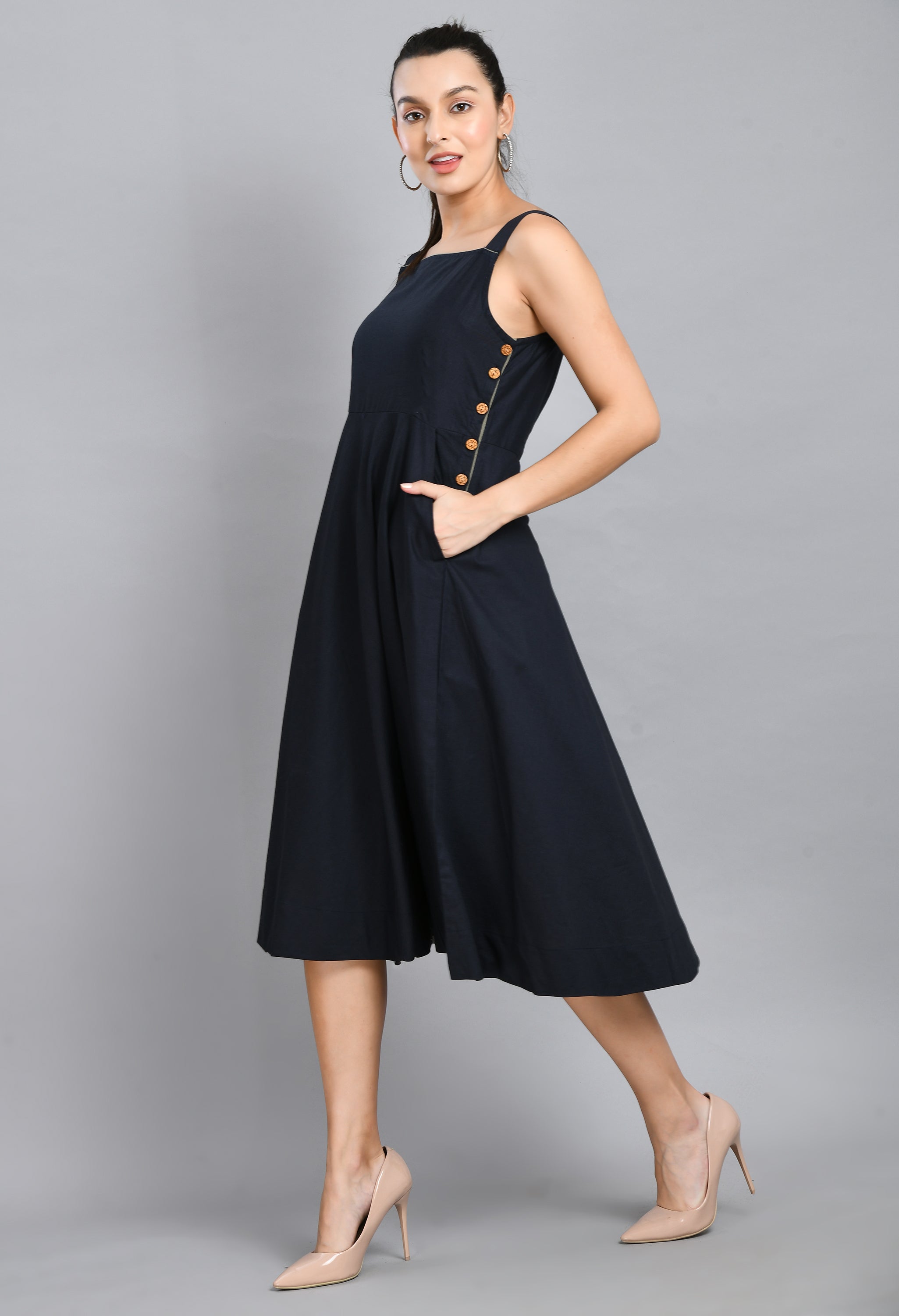 A stylish blue linen sleeveless dress with wood buttons and an asymmetrical hem, perfect for casual wear.