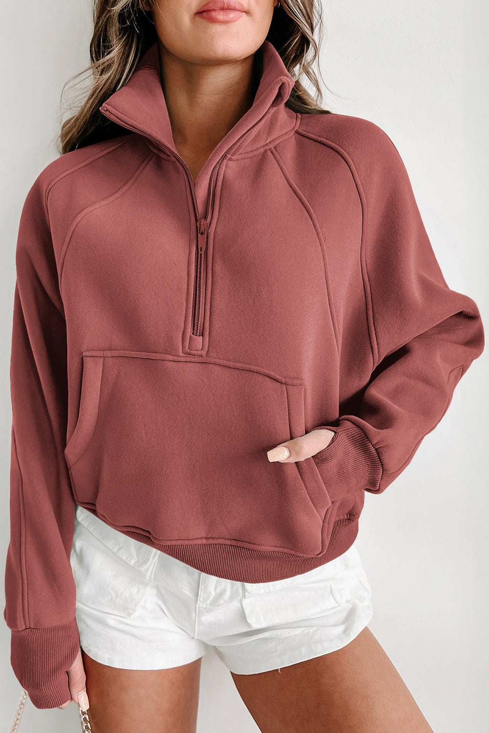 Brown zip-up sweatshirt with stand collar and thumbhole sleeves, featuring a textured design and kangaroo pocket.