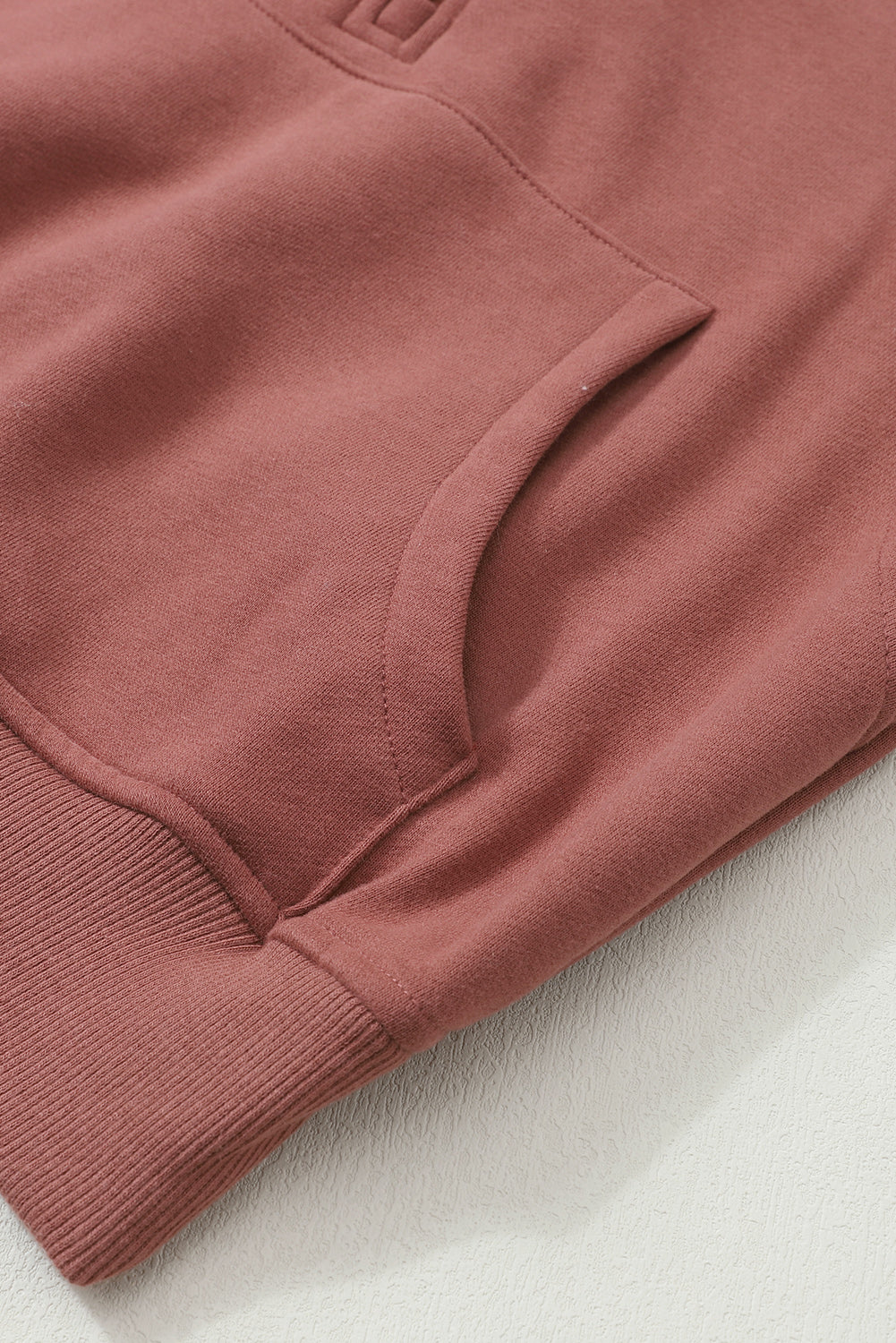 Brown zip-up sweatshirt with stand collar and thumbhole sleeves, featuring a textured design and kangaroo pocket.