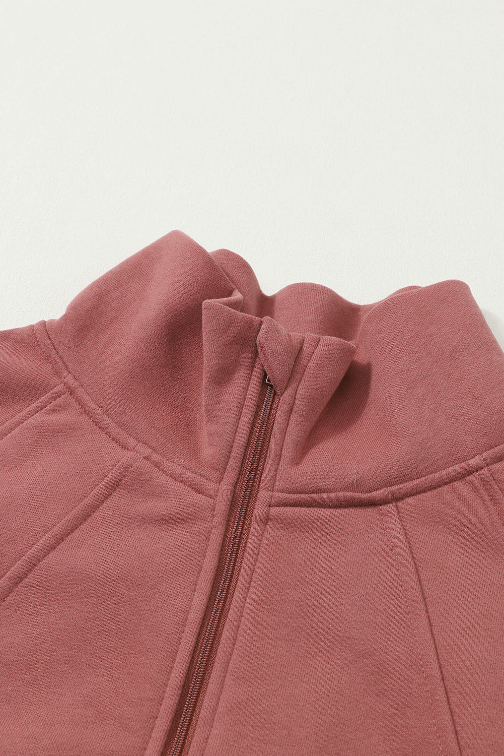 Brown zip-up sweatshirt with stand collar and thumbhole sleeves, featuring a textured design and kangaroo pocket.